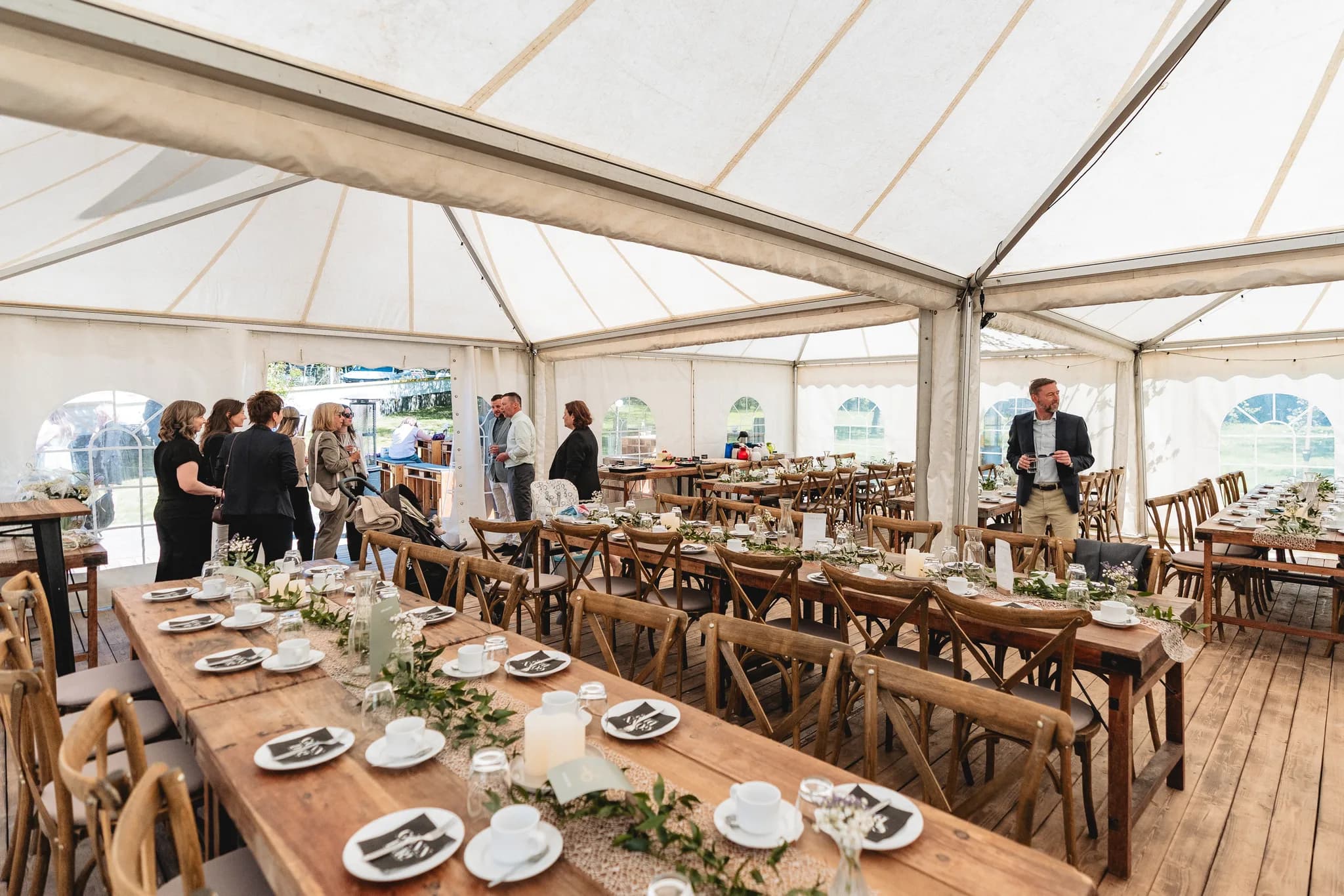 Gäste unterhalten sich in einem hellen Festzelt bei der Hochzeit von Stefanie und Ralf auf dem Gelände der Ulstermühle.