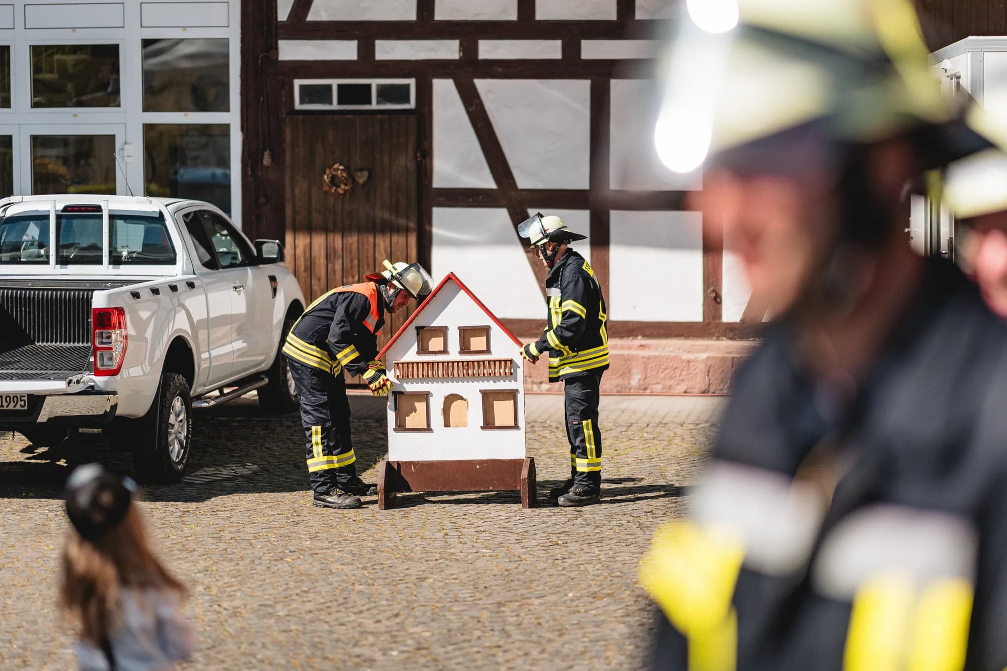 Zwei Feuerwehrleute tragen bei der Hochzeit von Stefanie und Ralf eine hölzerne Miniatur-Mühle über den Hof.