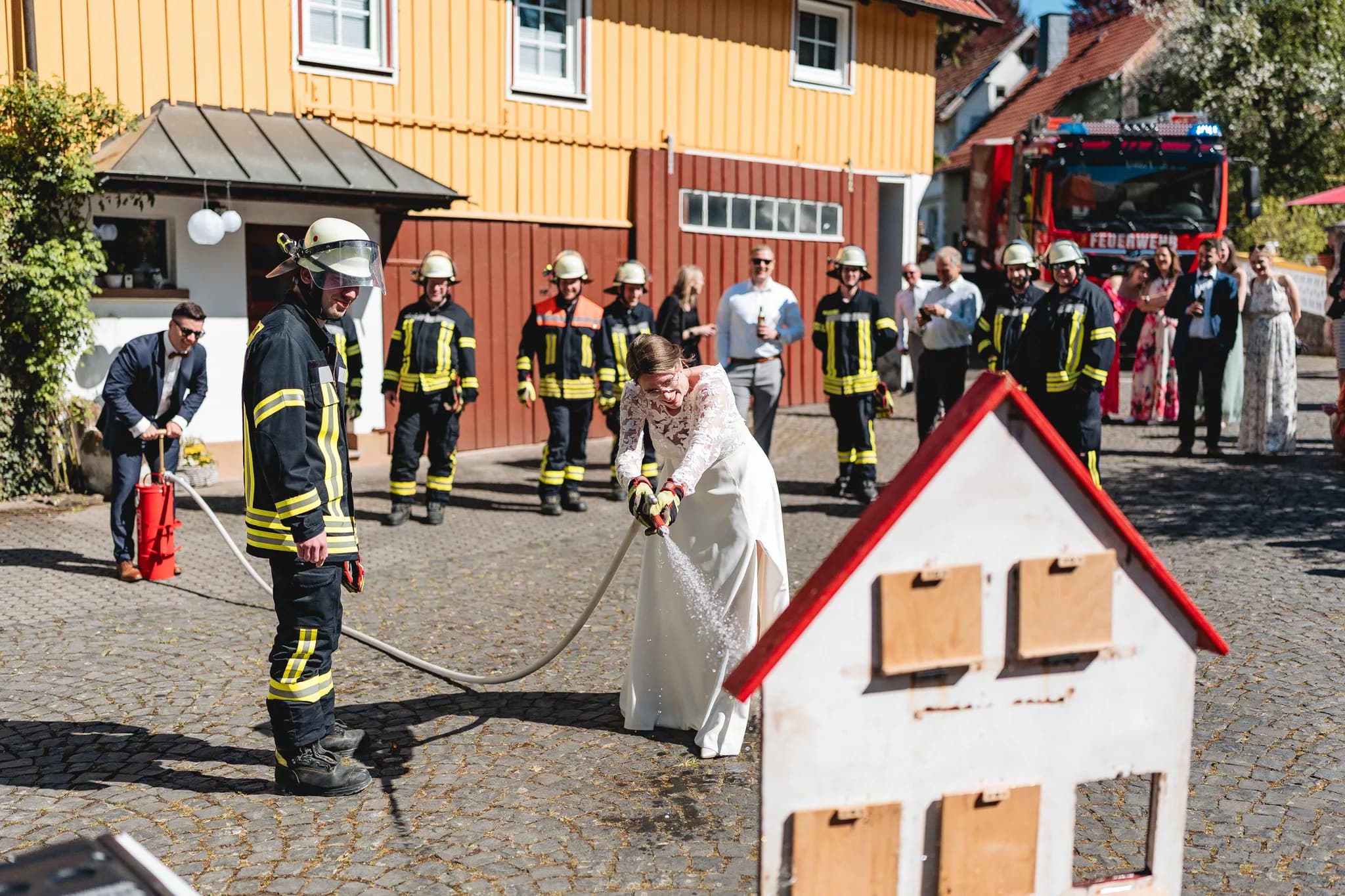 Braut Stefanie löscht bei der Hochzeitsfeier in der Ulstermühle mit Unterstützung der Feuerwehr ein kleines Holzhaus.