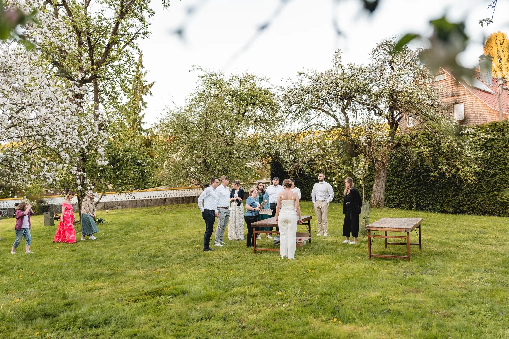 Hochzeitsgesellschaft versammelt sich im grünen Garten an der Ulstermühle zu Vorbereitungen für eine freie Trauung.