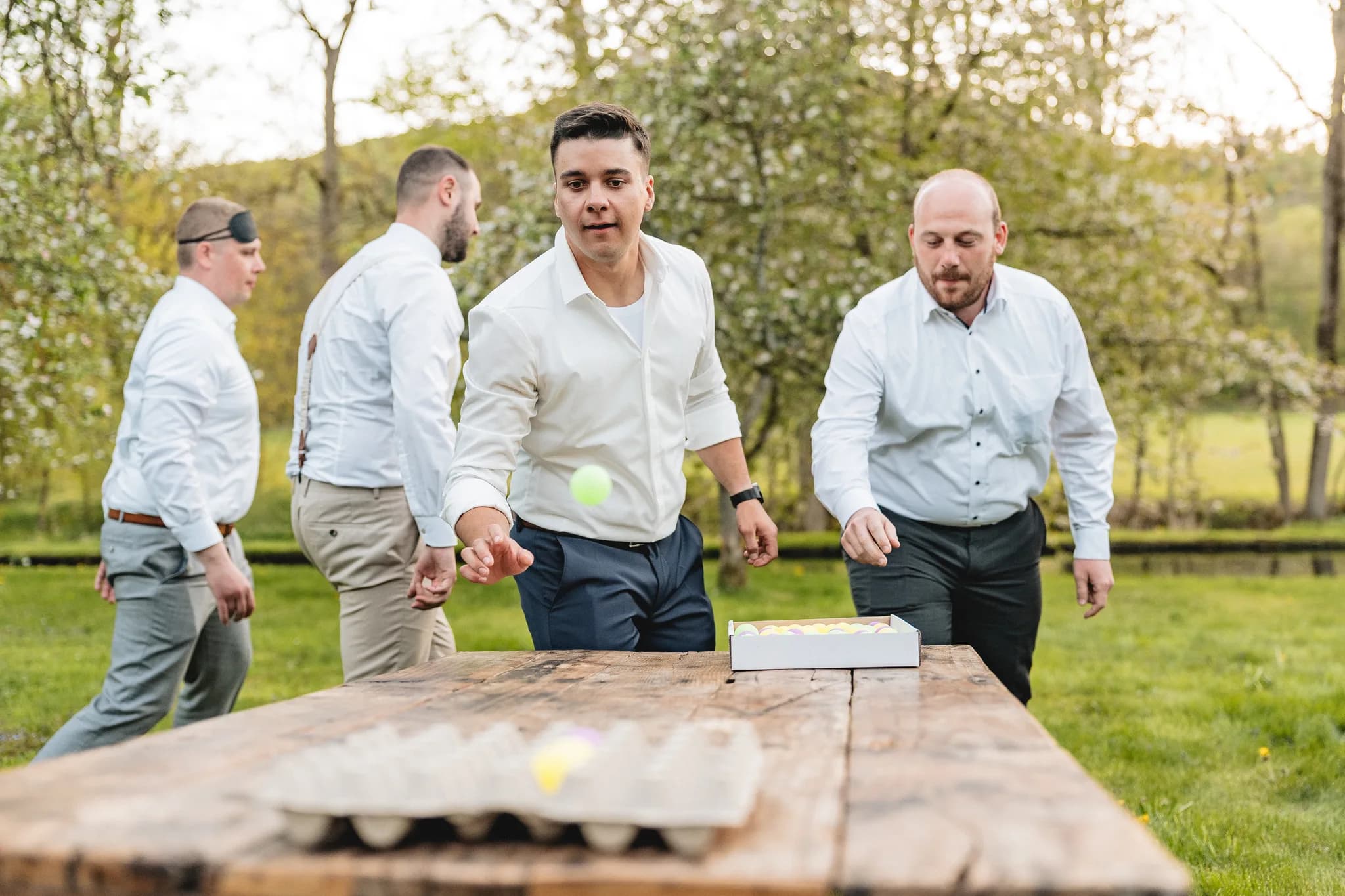 Brautigam und Freunde spielen bei der entspannten Gartenhochzeit in der Rhön gemeinsam ein Spiel mit kleinen Bällen.