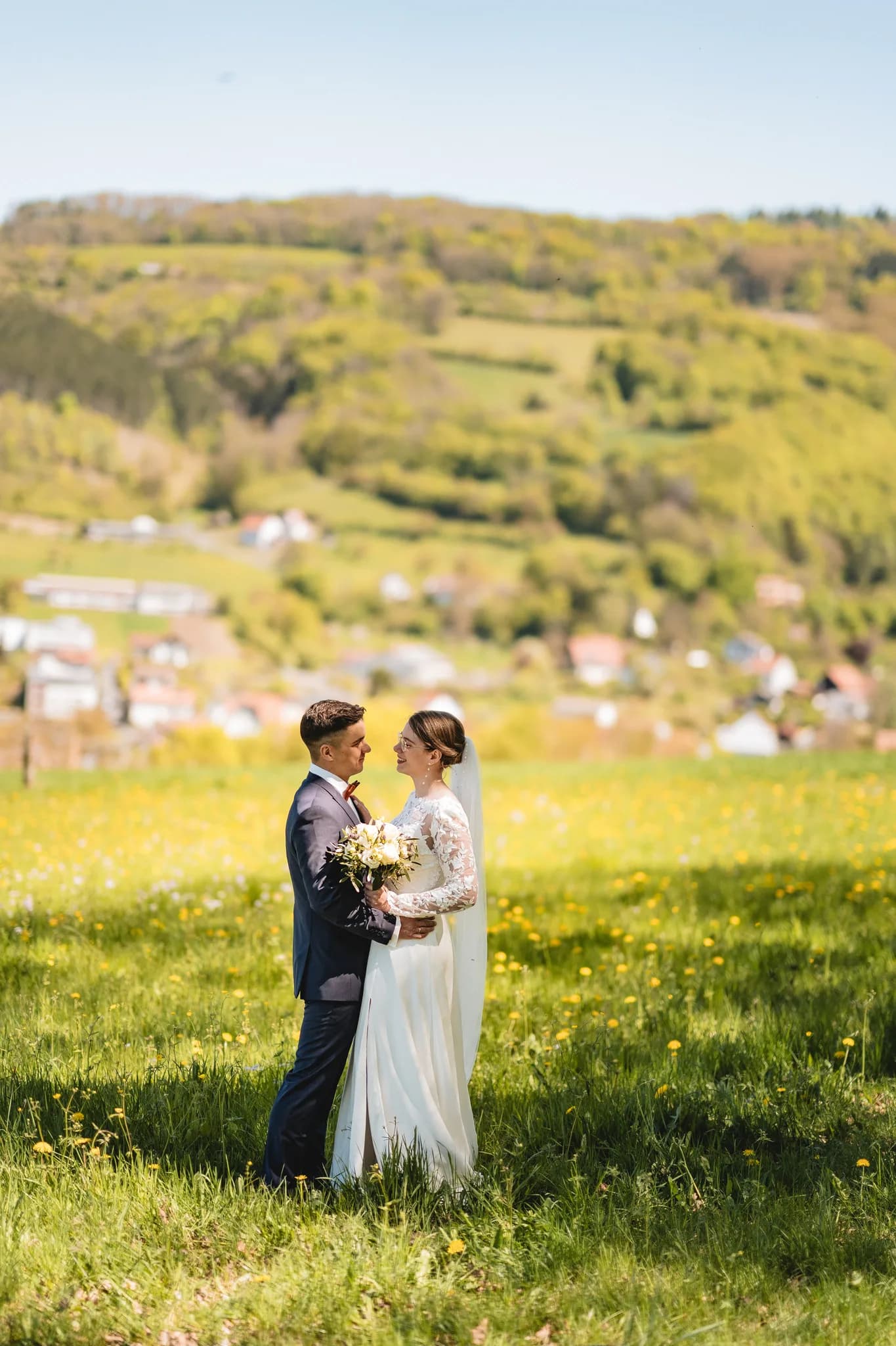 Stefanie und Ralf blicken sich bei ihrer freien Trauung auf einer blühenden Frühlingswiese in der Rhön liebevoll an.