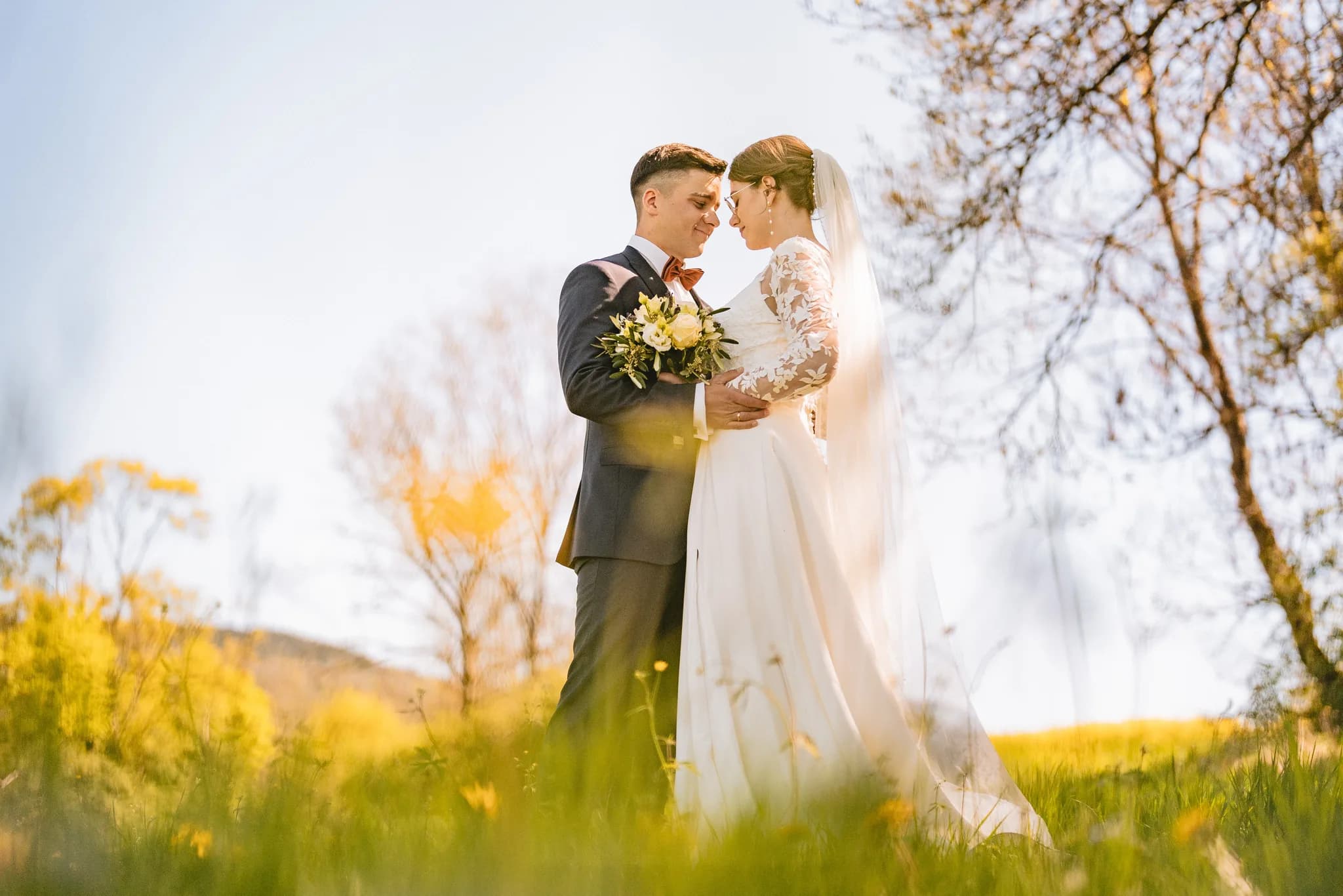 Stefanie und Ralf stehen sich bei strahlendem Maiwetter auf einer grünen Wiese in der Rhön liebevoll gegenüber.