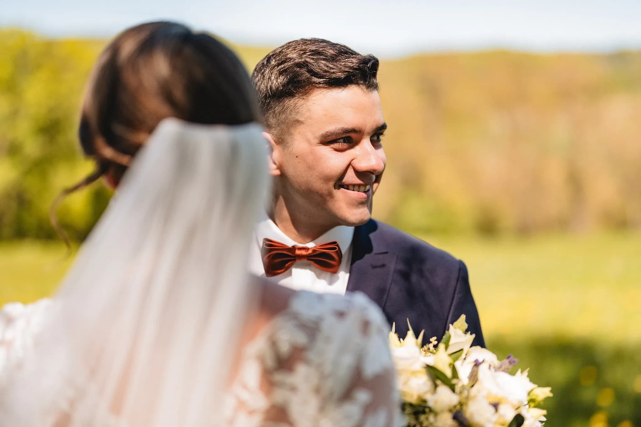 Stefanie und Ralf betrachten sich glücklich bei ihrer freien Trauung auf einer sonnigen Wiese in der Rhön.