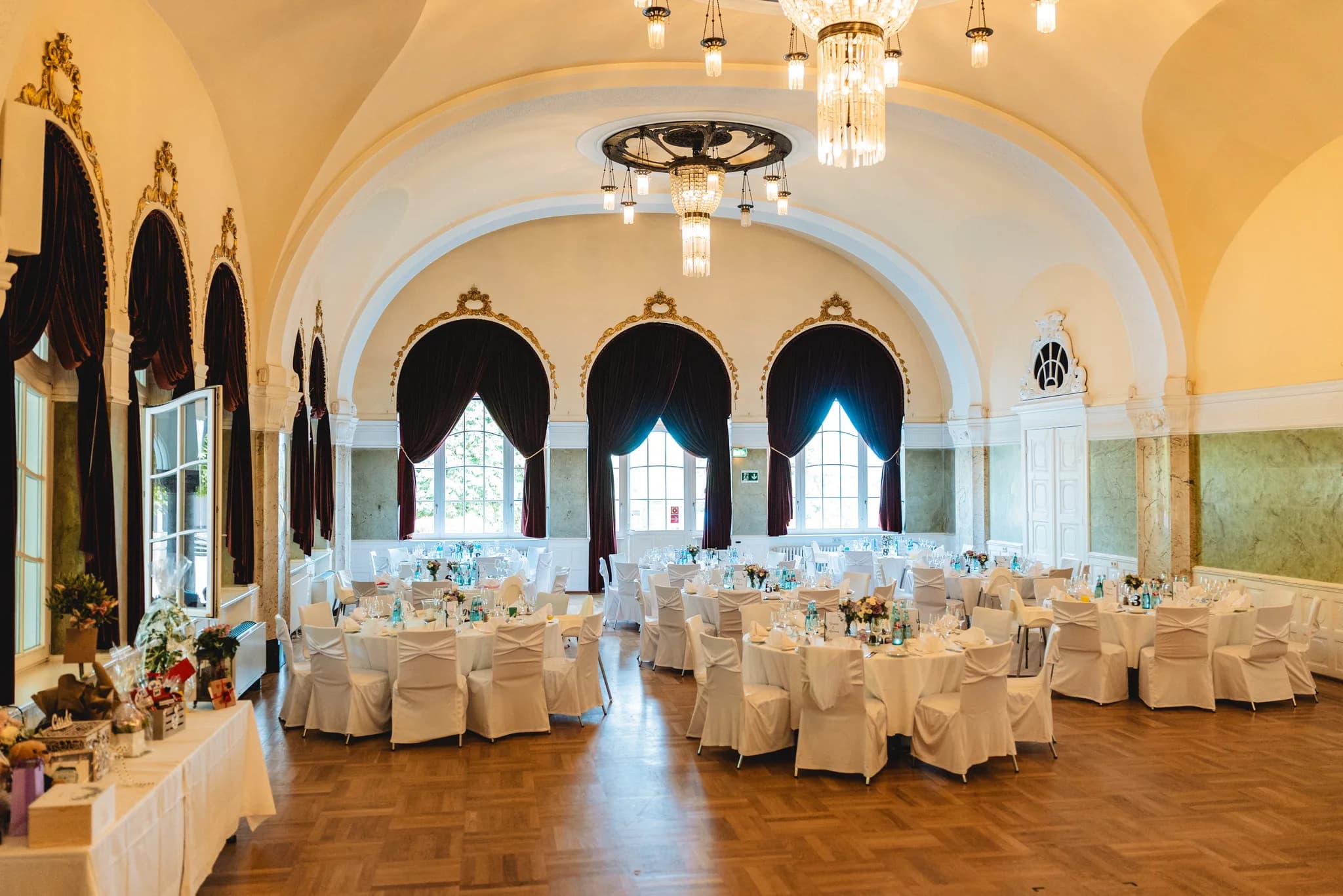 Festlich eingedeckte Hochzeitstafeln im prunkvollen, lichtdurchfluteten Ballsaal des Dolce by Wyndham Bad Nauheim.