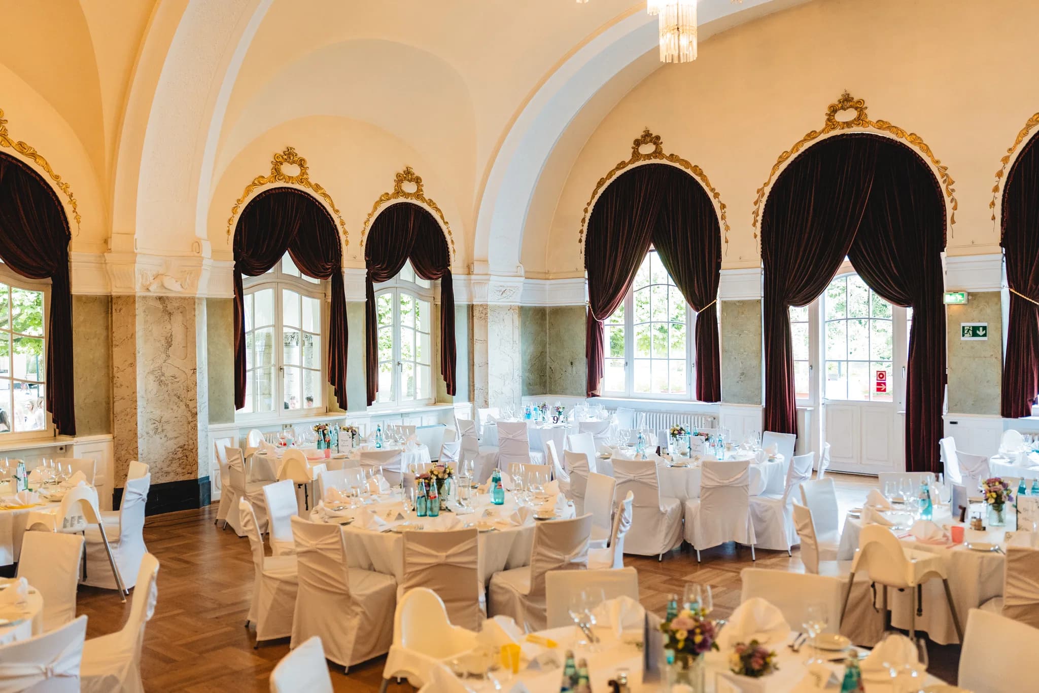 Festlich eingedeckte Rundtische im historischen Ballsaal des Dolce by Wyndham Bad Nauheim vor hohen Bogenfenstern.