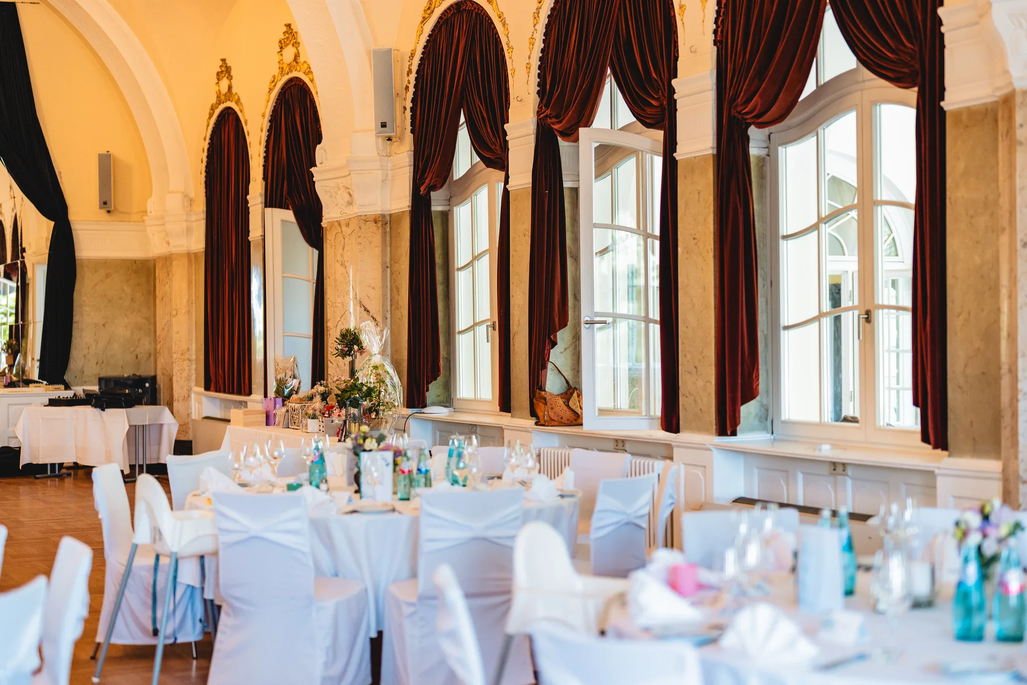 Festlich gedeckte Hochzeitstische mit weißen Hussen in einem eleganten Saal des Dolce by Wyndham in Bad Nauheim.
