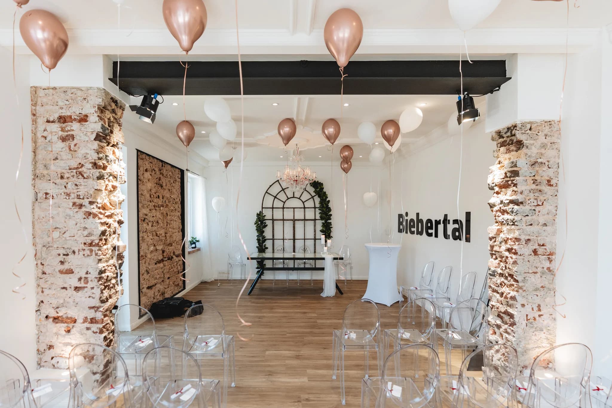 Festlich geschmückter Trauraum mit transparenten Stühlen und schwebenden Luftballons in einer Location in Hofbieber.