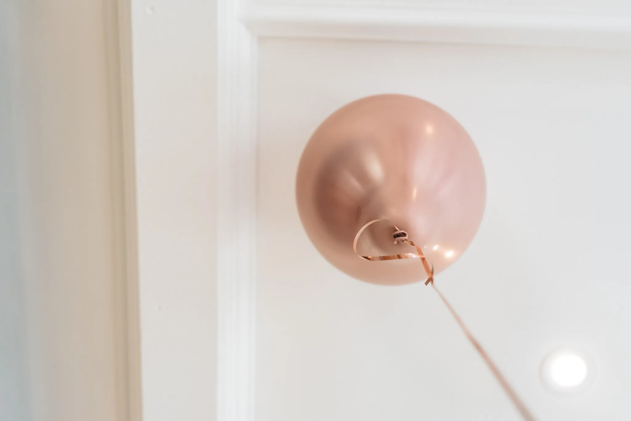 Ein einzelner, roségoldener Luftballon schwebt an einem Band vor einem hellen Raum in Hofbieber.