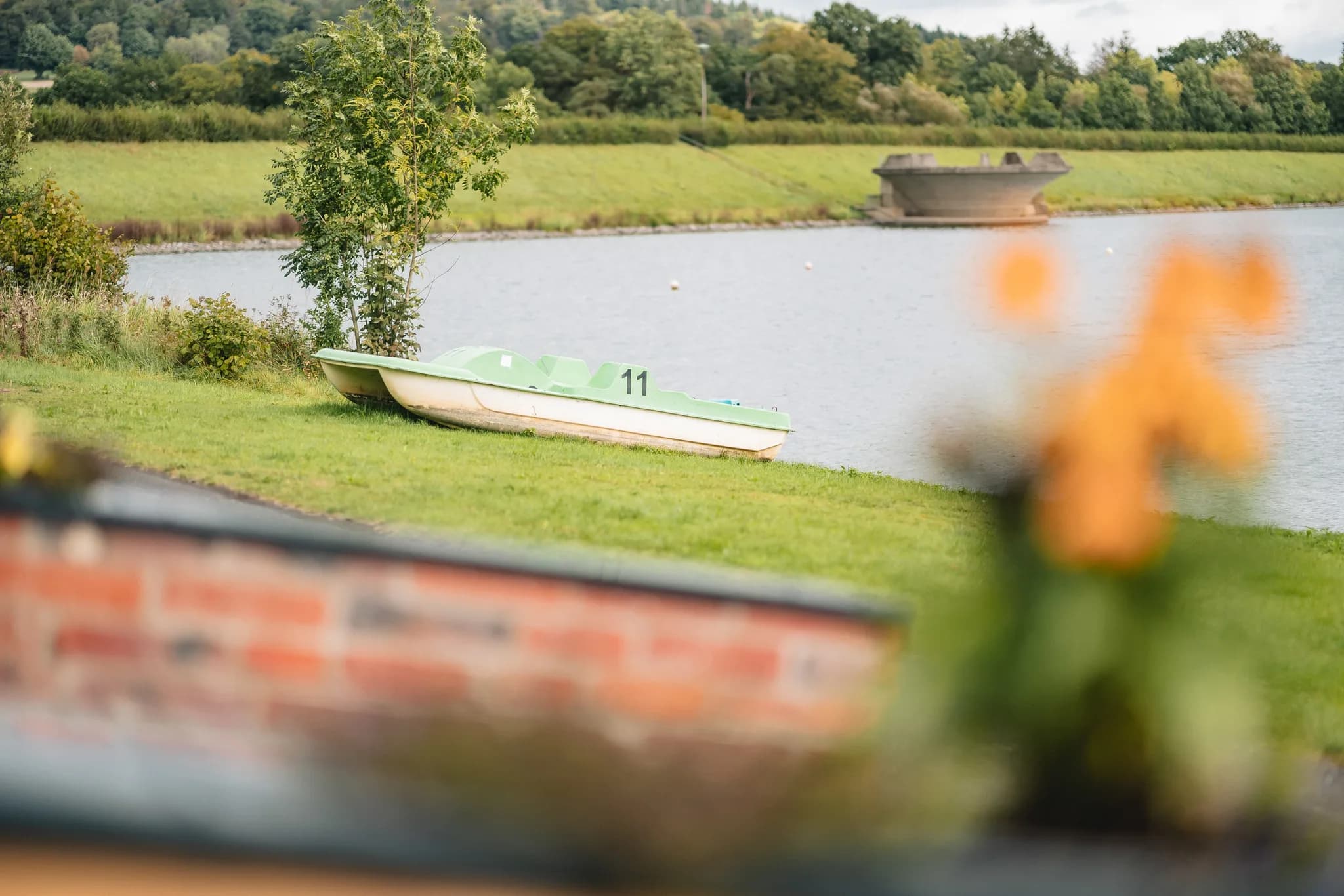 Ein hellgrünes Tretboot mit der Nummer 11 liegt am grasbewachsenen Ufer des Lakeside Resort Michaela.