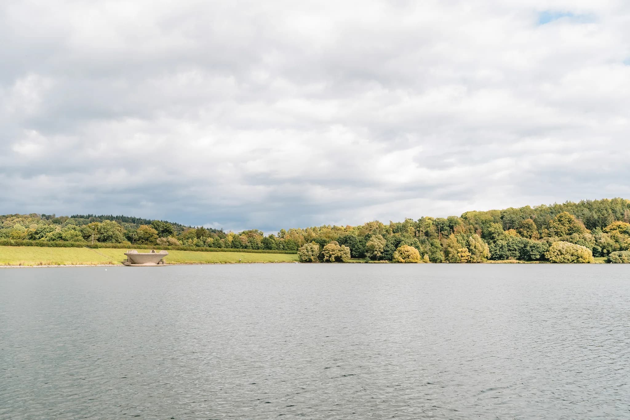 Blick über den See des Lakeside Resort Michaela auf die bewaldete Uferlandschaft unter einem bewölkten Himmel.