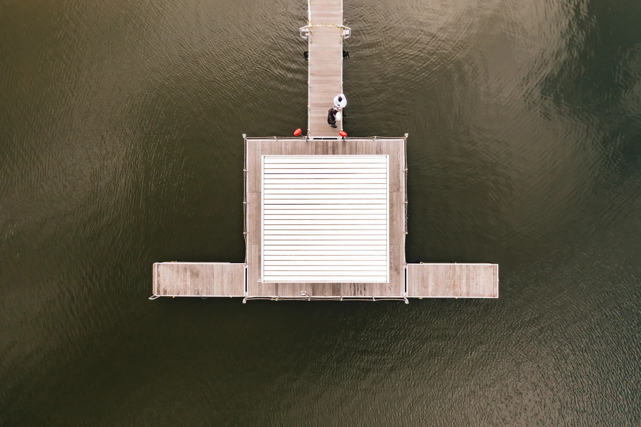 Draufsicht auf das Brautpaar, das auf einem Holzsteg im Wasser vor dem Lakeside Resort Michaela steht.