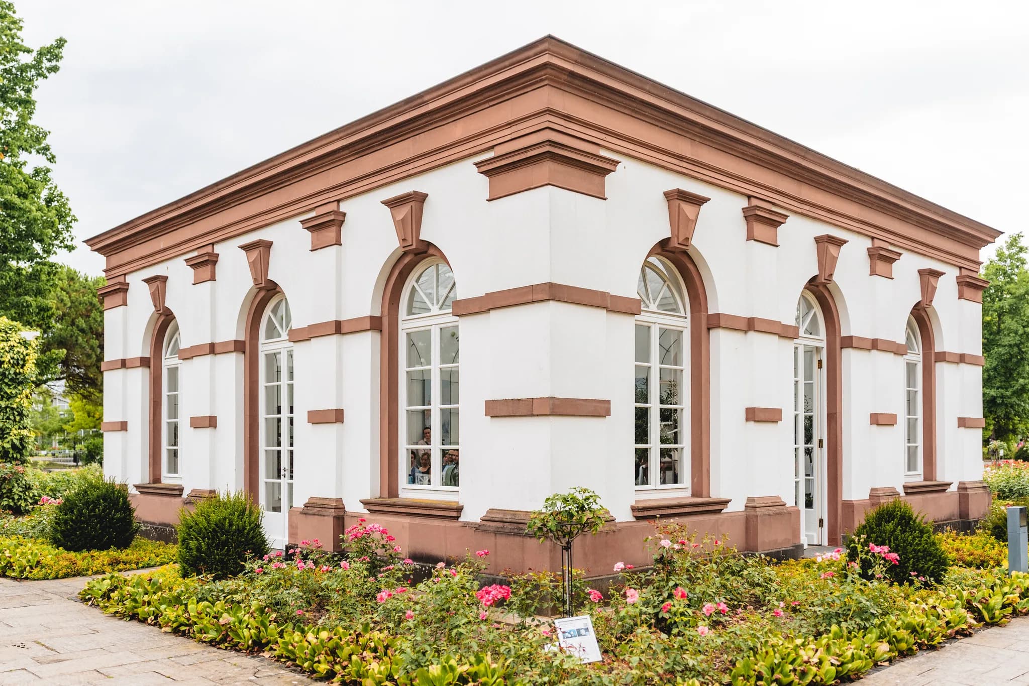 Das klassizistische Gebäude im Palmengarten Frankfurt ist von einem blühenden Rosengarten umgeben.