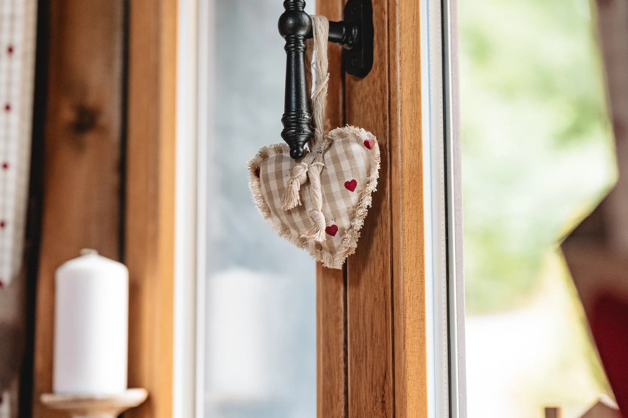 Ein Herzanhänger aus Stoff mit kleinen roten Herzen hängt an einem Fenstergriff in Kleinlüder.