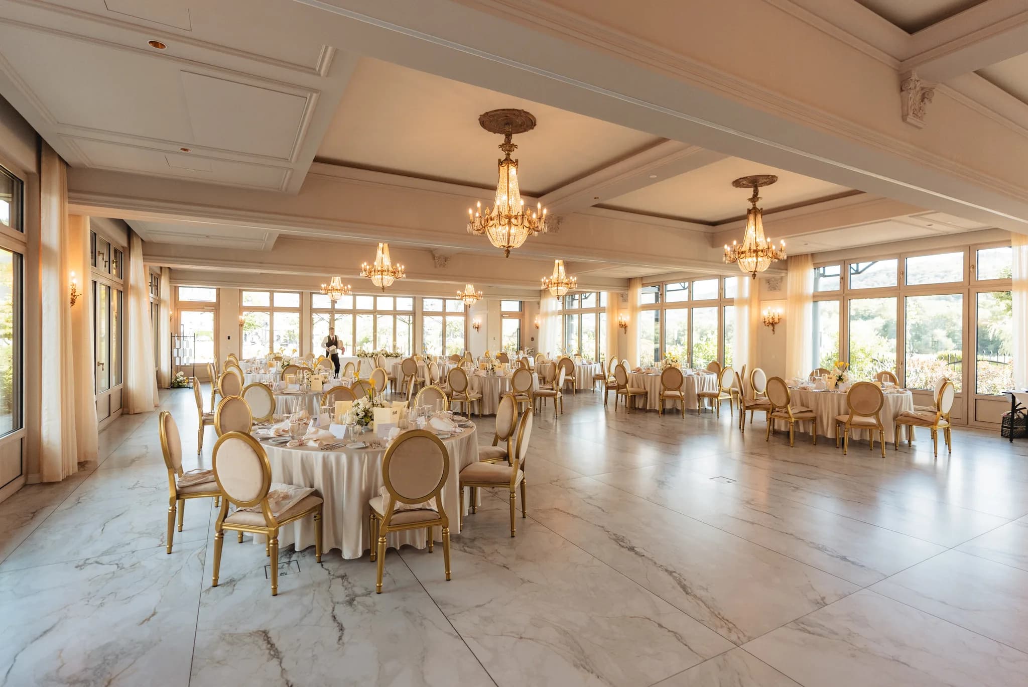 Festlich gedeckte Tische in einem eleganten Hochzeitssaal mit Kronleuchtern und Marmorboden in Lieser an der Mosel.