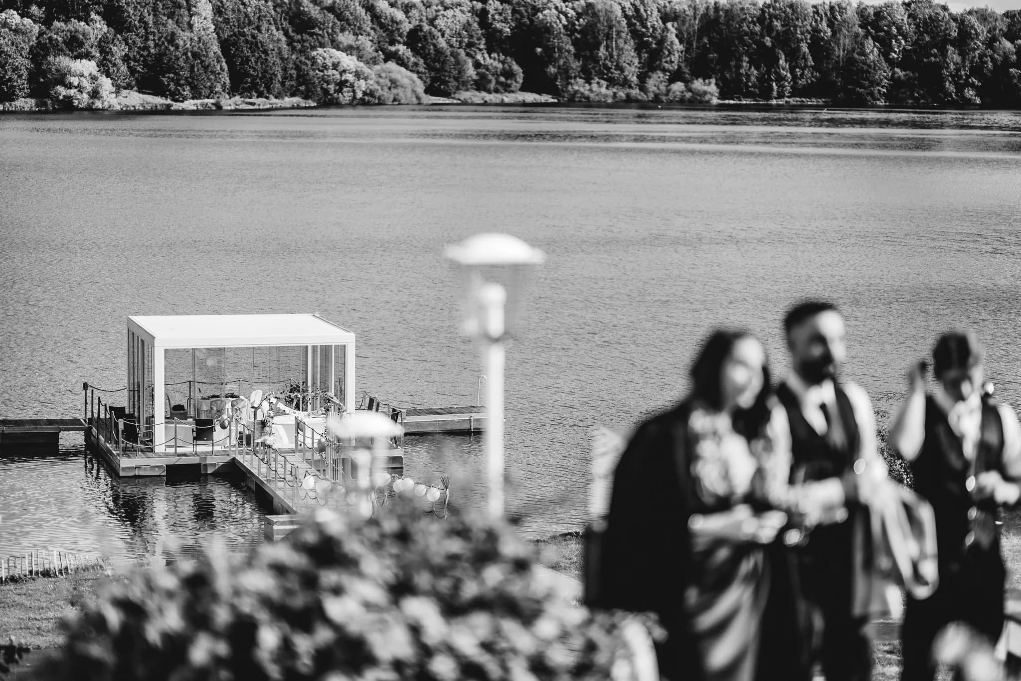Peggy und Daniel in einer unscharfen Aufnahme vor der festlich geschmückten Hochzeitsplattform im Lakeside Resort.
