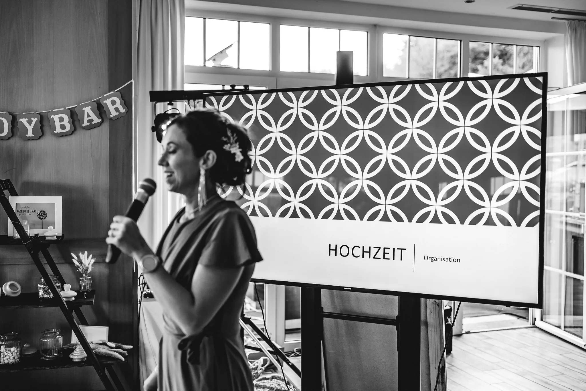 Eine Frau hält während der Hochzeitsfeier von Peggy und Daniel im Lakeside Resort eine Rede mit einem Mikrofon.