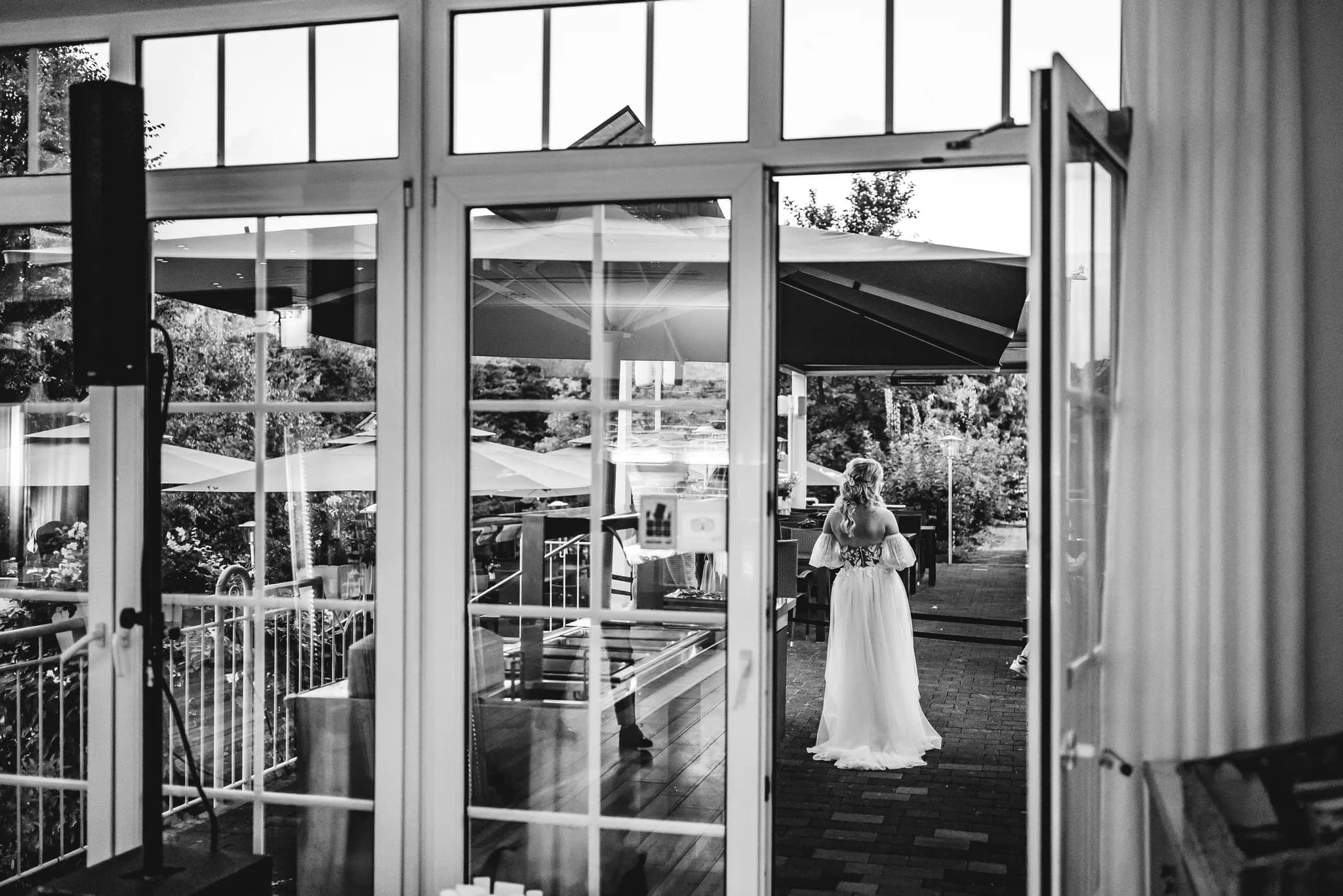 Peggy steht in ihrem Brautkleid auf der Terrasse des Lakeside Resort Michaela und blickt hinaus in den Garten.