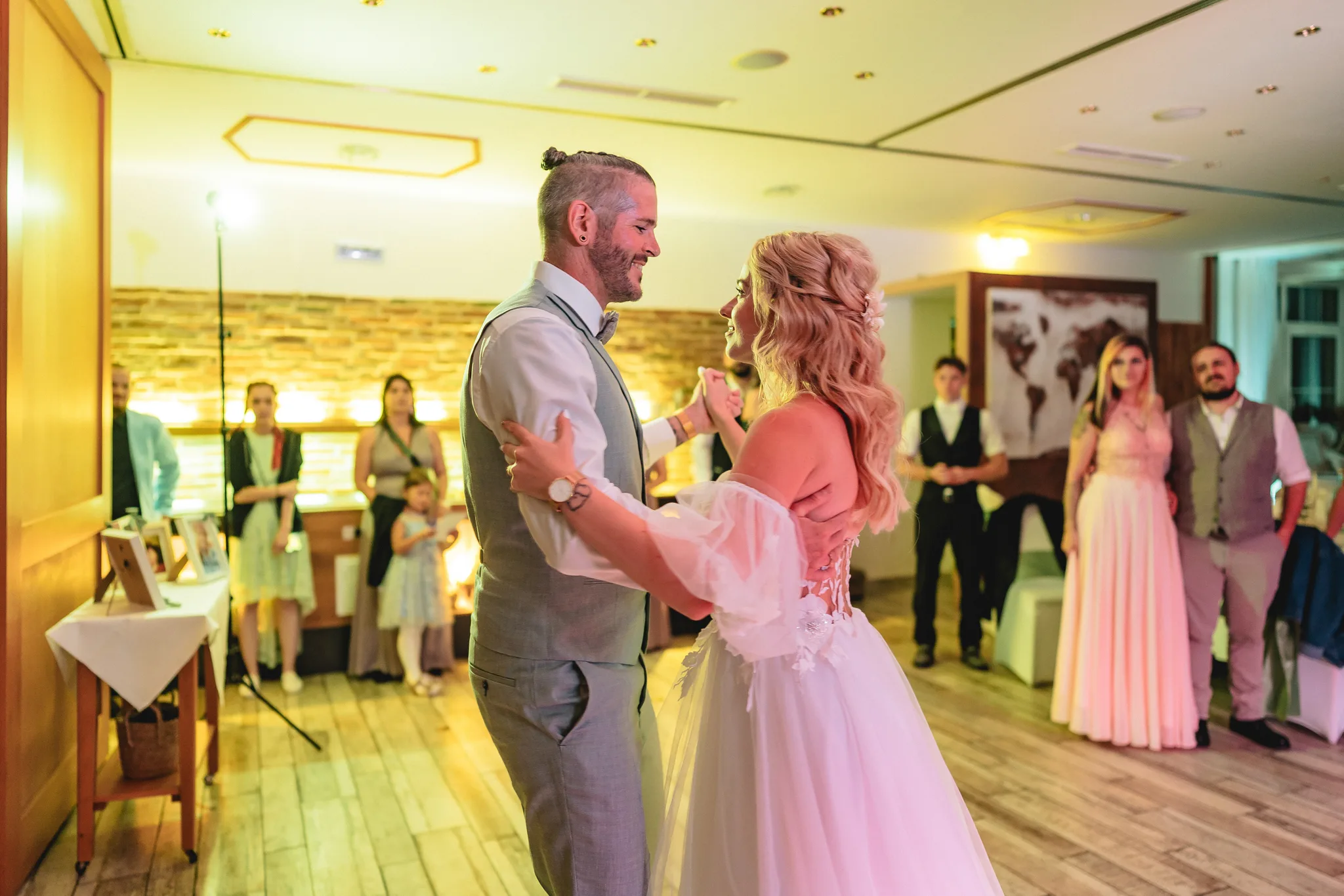 Peggy und Daniel tanzen glücklich ihren Hochzeitstanz während ihre Gäste im Lakeside Resort Michaela zusehen.