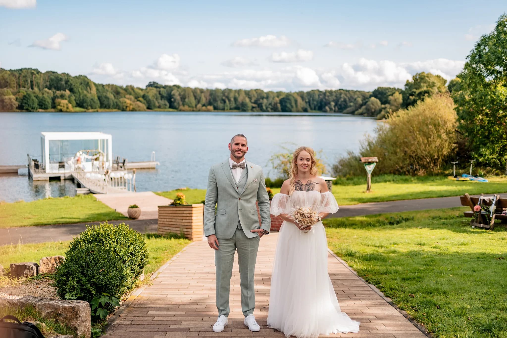 Brautpaar Peggy und Daniel stehen gemeinsam auf einem Weg vor dem See im Lakeside Resort Michaela.