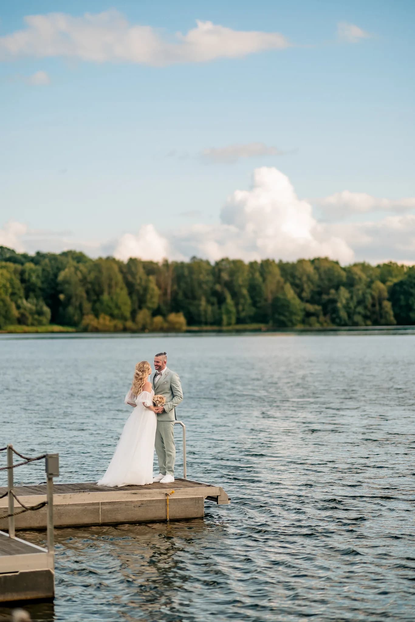 Brautpaar Peggy und Daniel stehen sich liebevoll anblickend auf einem Holzsteg am Lakeside Resort Michaela gegenüber.