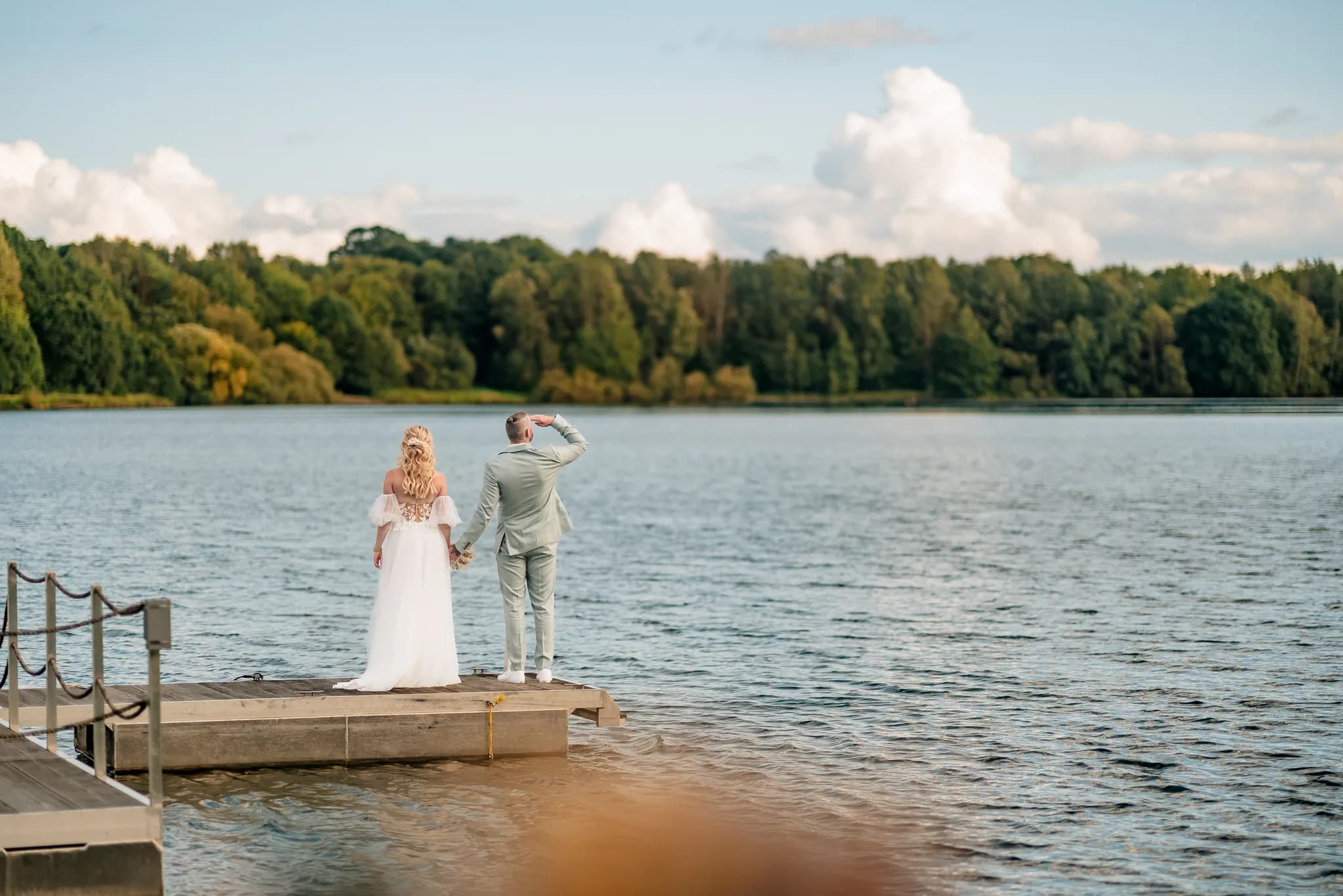 Peggy und Daniel stehen händchenhaltend auf einem Steg am Lakeside Resort Michaela und blicken gemeinsam auf den See.