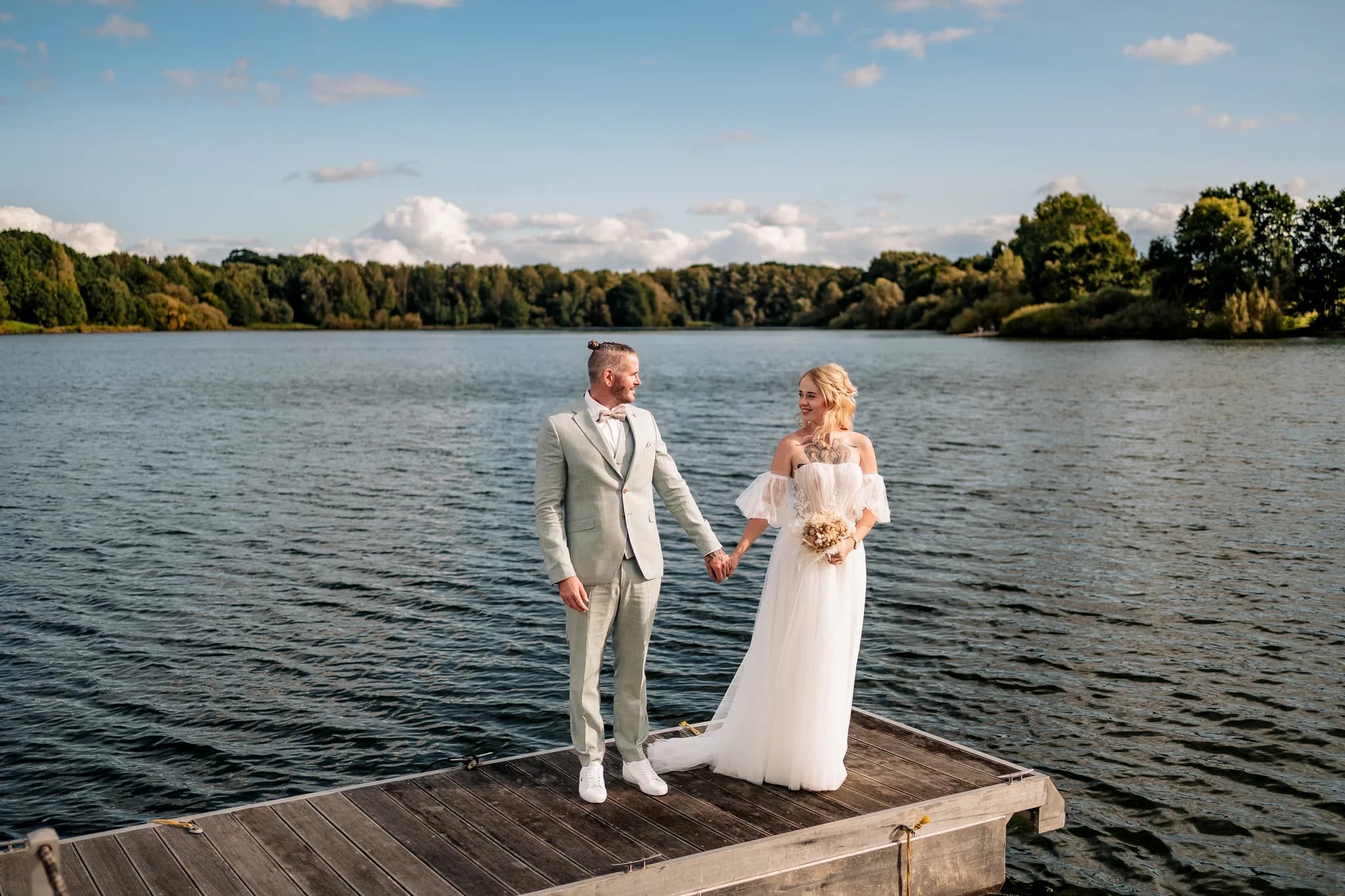 Brautpaar Peggy und Daniel hält sich liebevoll an den Händen auf einem Bootssteg am Lakeside Resort Michaela.