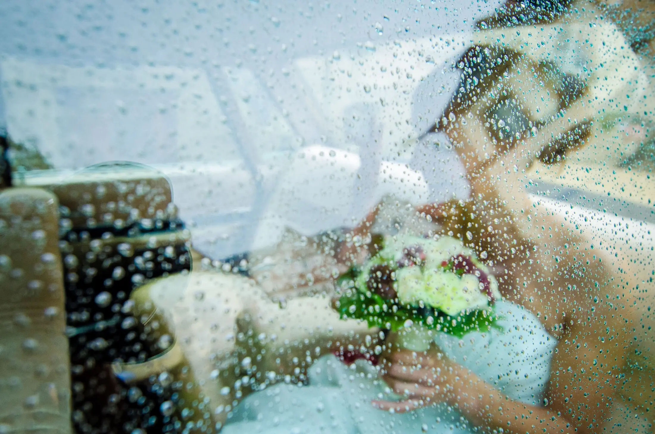 Brautpaar sitzt im Auto, während es regnet. 